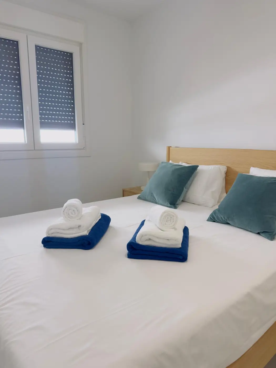 Made bedroom with blue cushions and folded towels